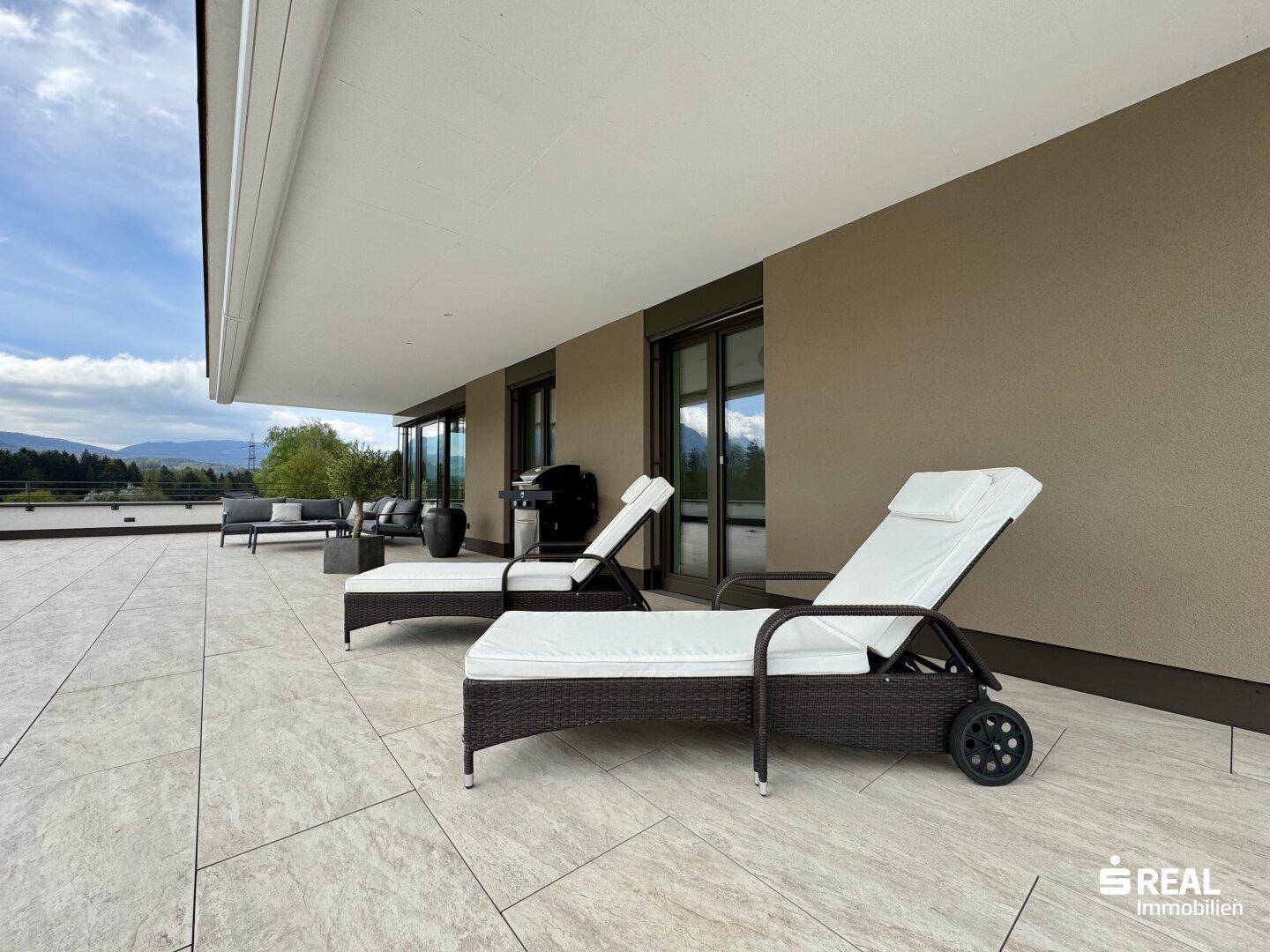 Überdachter Terrassenbereich mit Liegestühlen und Blick auf die umliegende Natur.