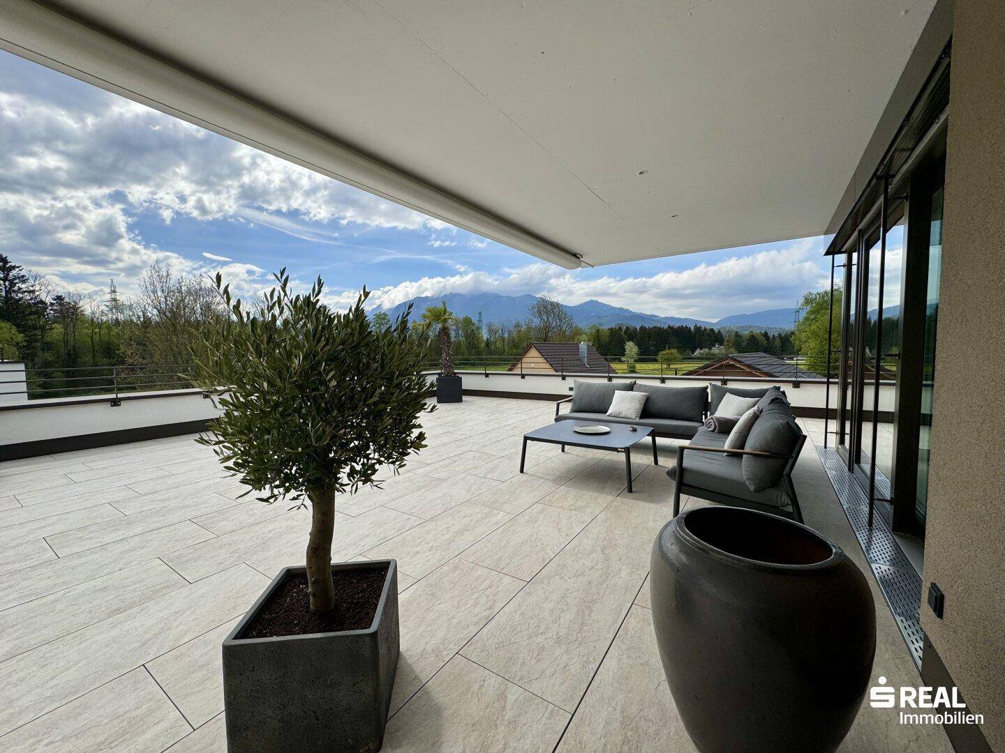Gemütliche Dachterrasse mit Loungemöbeln, Olivenbaum und weitem Blick auf die umliegende Natur.