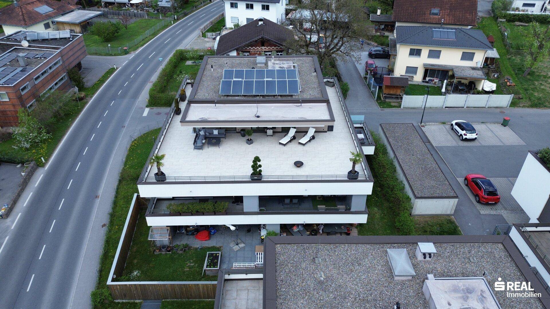 Luftaufnahme der modernen Wohnanlage mit Dachterrassen und Photovoltaikanlage.