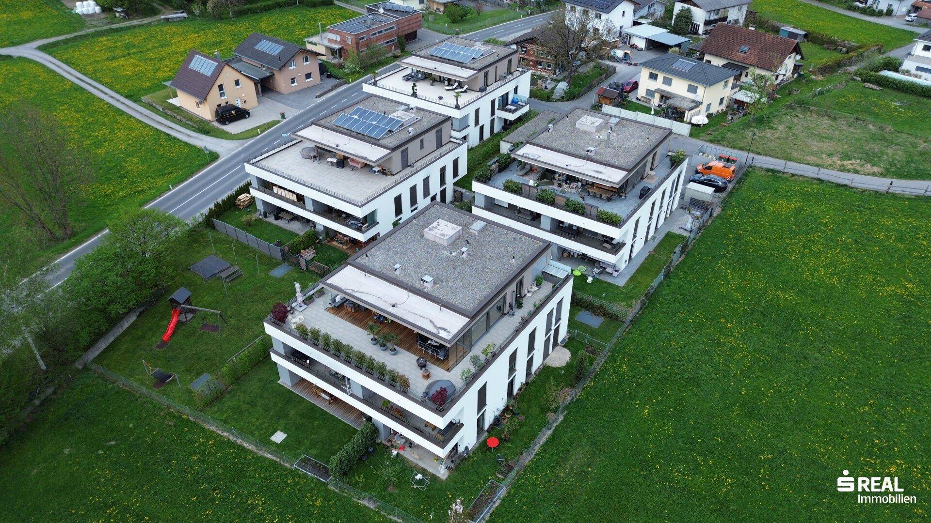 Luftaufnahme einer modernen Wohnsiedlung mit mehreren Gebäuden und Grünflächen.