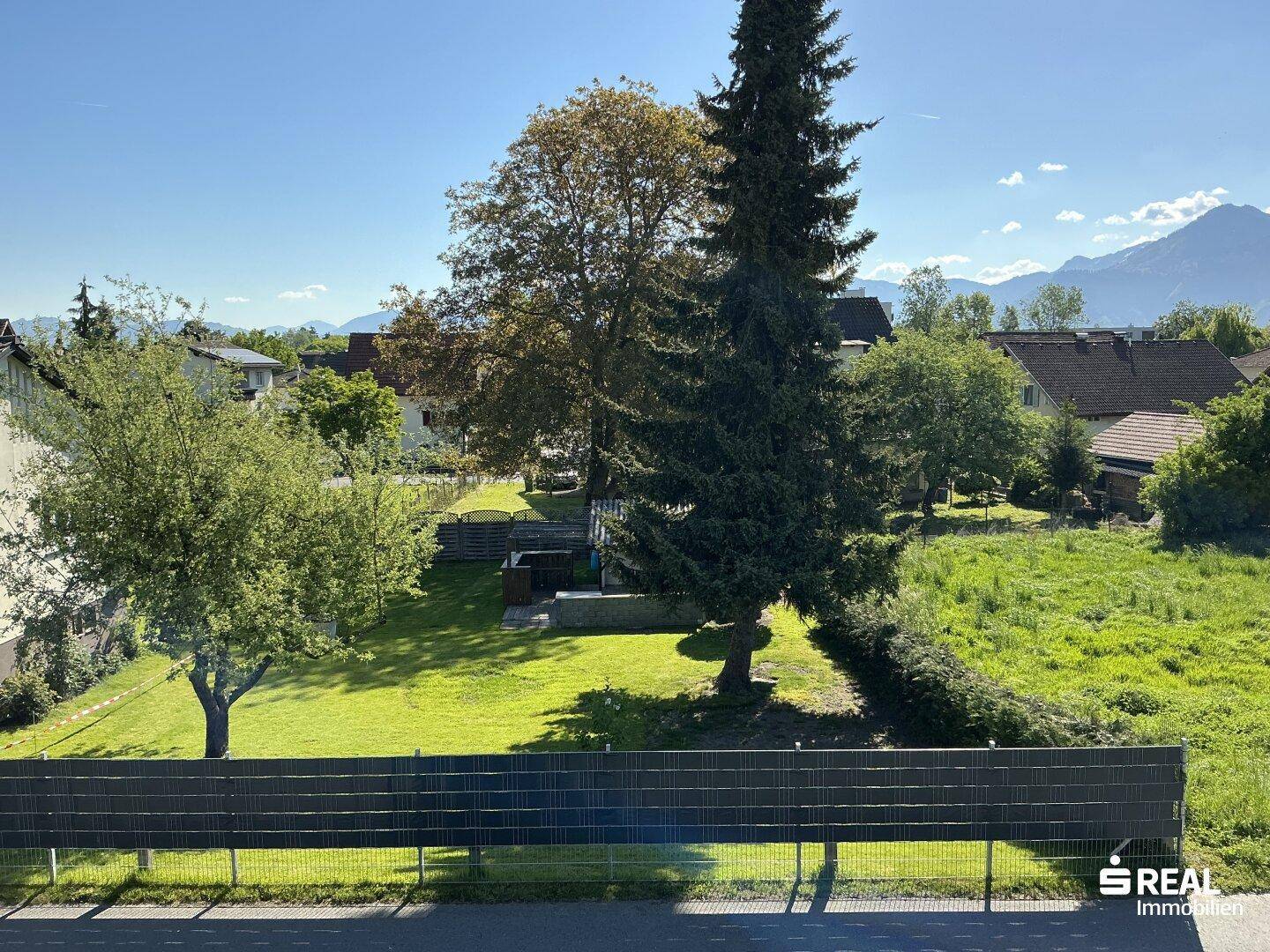 Weitläufiger Blick über den Garten und die umliegende Landschaft bis hin zu den majestätischen Bergen.