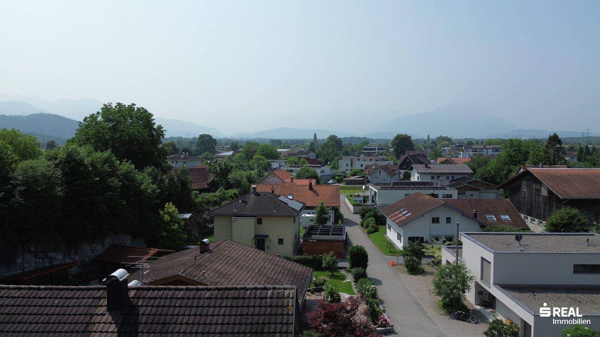 Weitläufiger Blick über die Dächer der Nachbarschaft bis zu den fernen Bergen am Horizont.