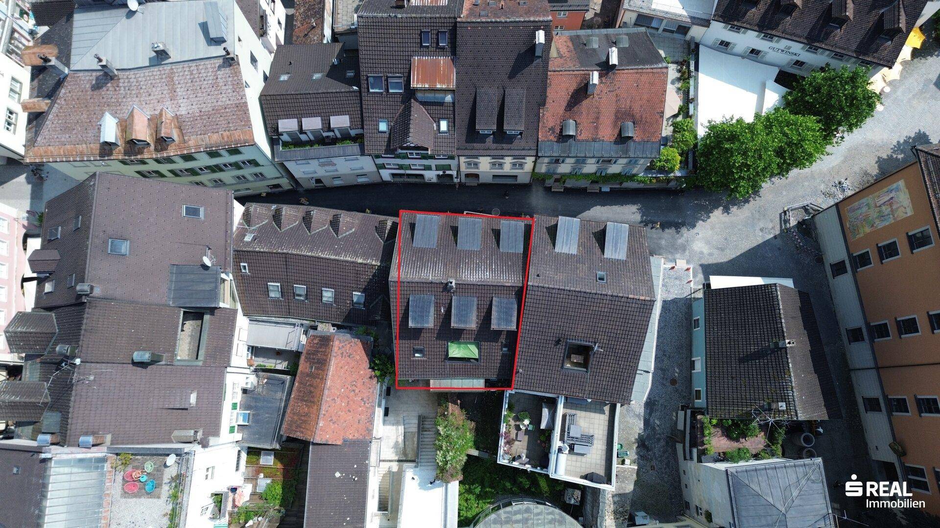 Luftaufnahme einer Altstadt mit markiertem Gebäude und umliegenden Dächern, städtische Struktur.