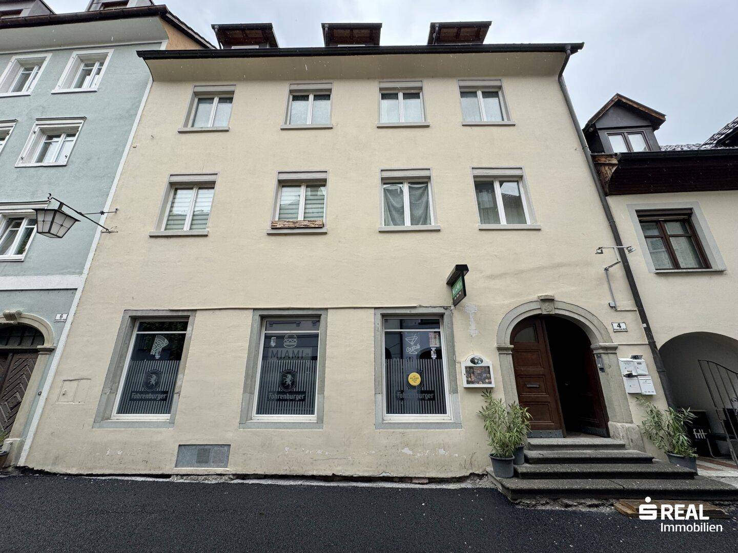 Fassade eines historischen Gebäudes mit mehreren Fenstern und einem bogenförmigen Eingangsbereich.