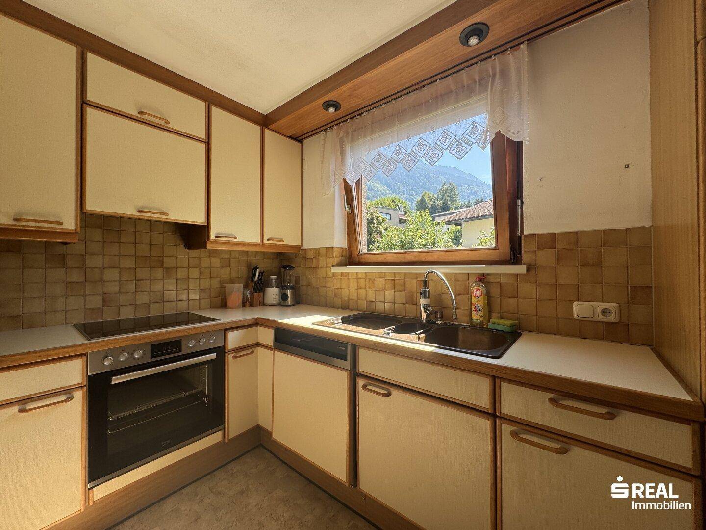 Helle Küche mit Einbauschränken, Fenster mit Bergblick und integrierten Geräten.