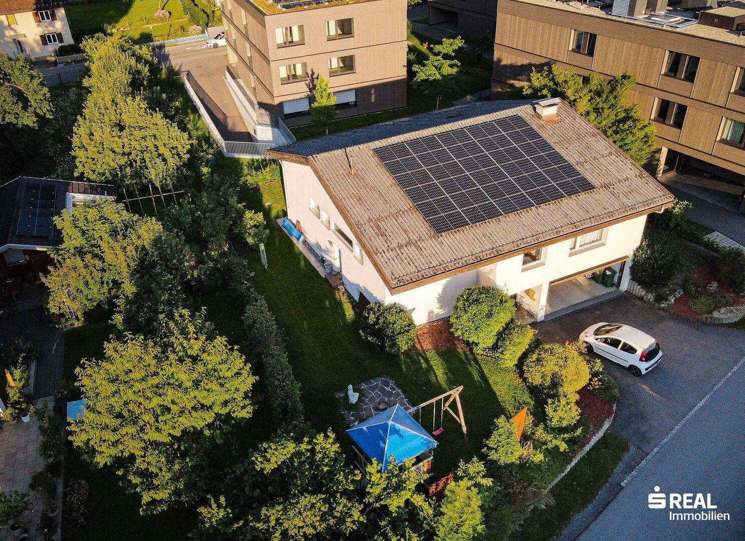 Luftaufnahme eines Hauses mit Solaranlage auf dem Dach und einem Garten mit Spielplatz.