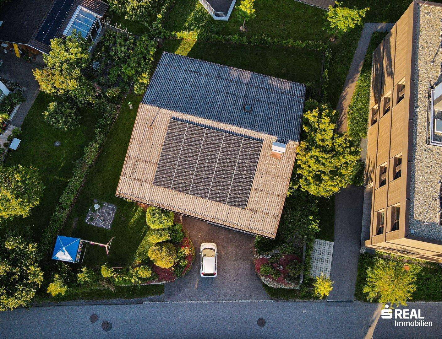 Draufsicht auf das Haus mit Solarmodulen auf dem Dach und einem Auto auf der Einfahrt.