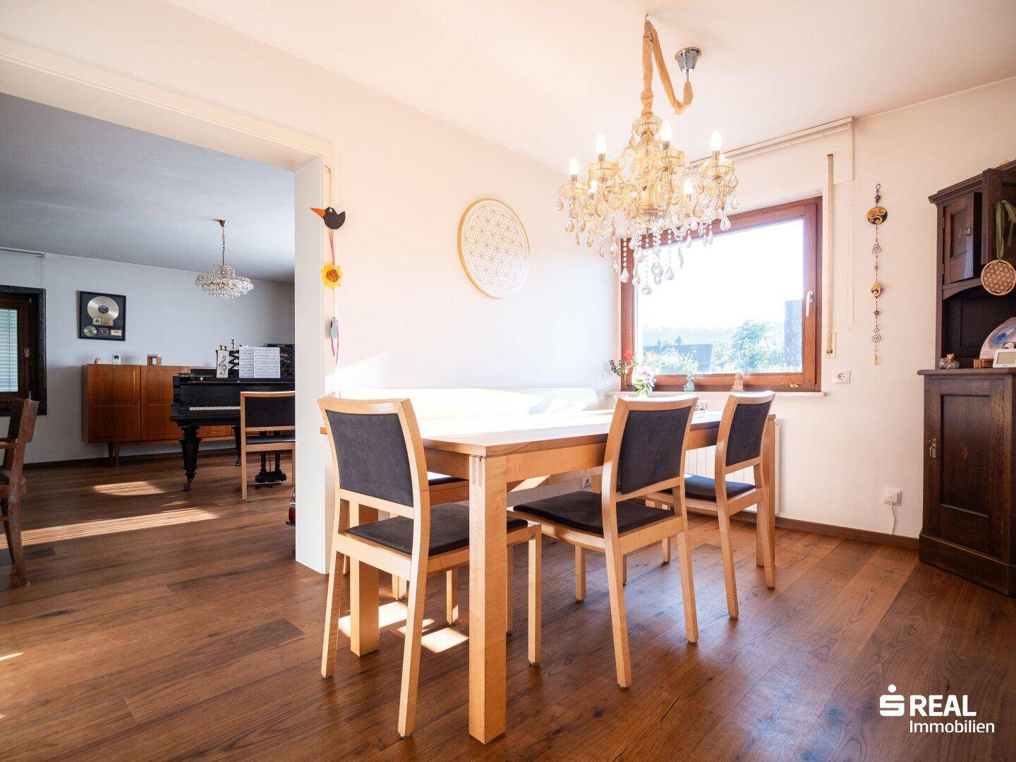 Heller Essbereich mit Holztisch, Stühlen und Kronleuchter, offen zum Wohnzimmer.