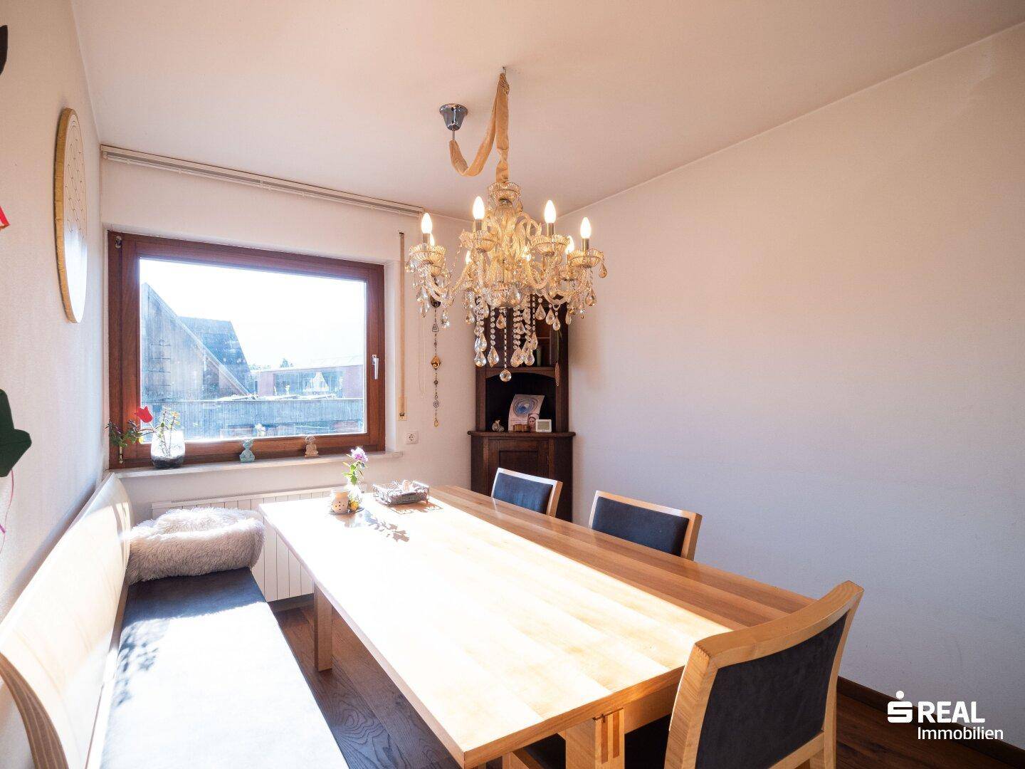 Gemütlicher Essbereich mit langer Holzbank, Esstisch und elegantem Kronleuchter.
