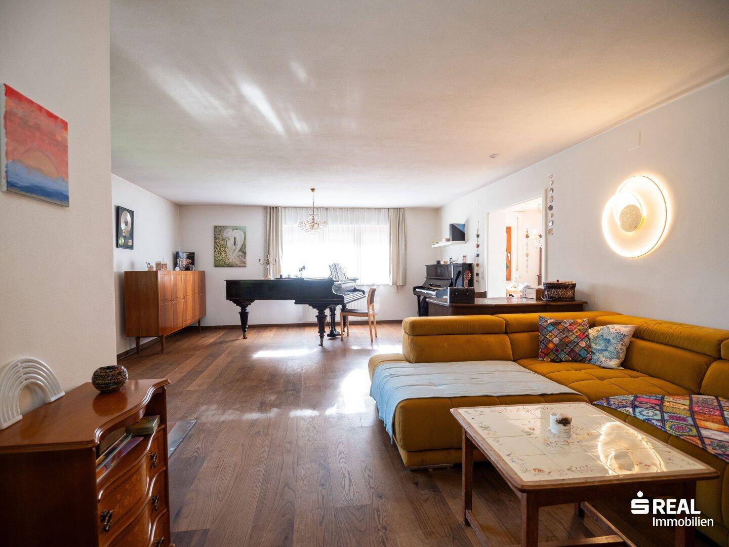 Weitläufiges Wohnzimmer mit gelbem Sofa, Flügel und eleganten Holzmöbeln.