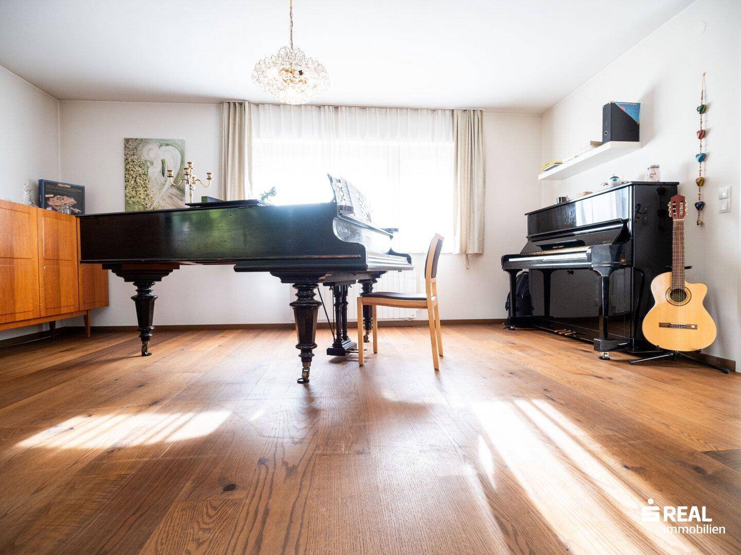 Helles Wohnzimmer mit glänzendem Holzboden, Flügel und Klavier.