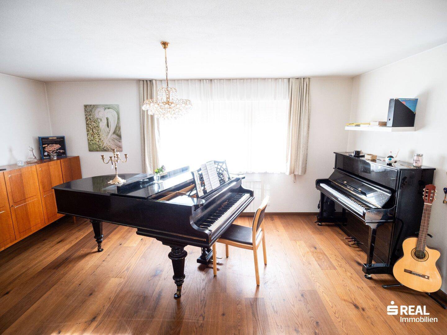 Elegantes Wohnzimmer mit Flügel, Klavier und funkelndem Kronleuchter.