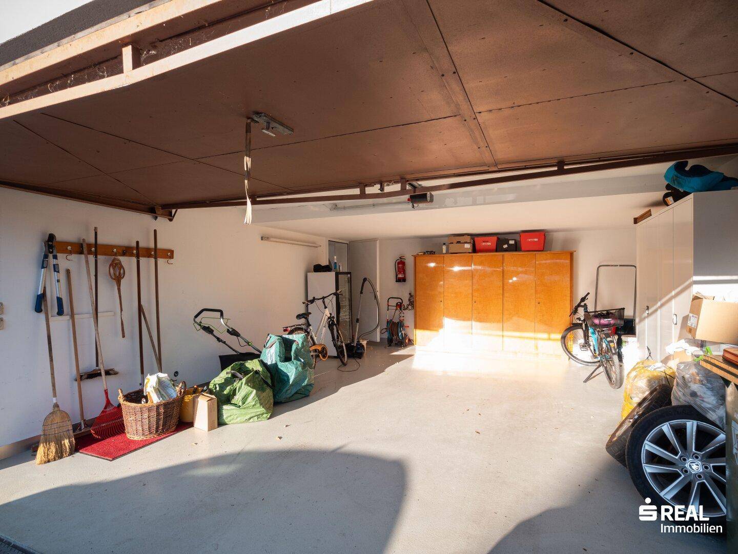 Geräumige Garage mit Betonboden, viel Stauraum und Platz für Fahrräder und Werkzeuge.