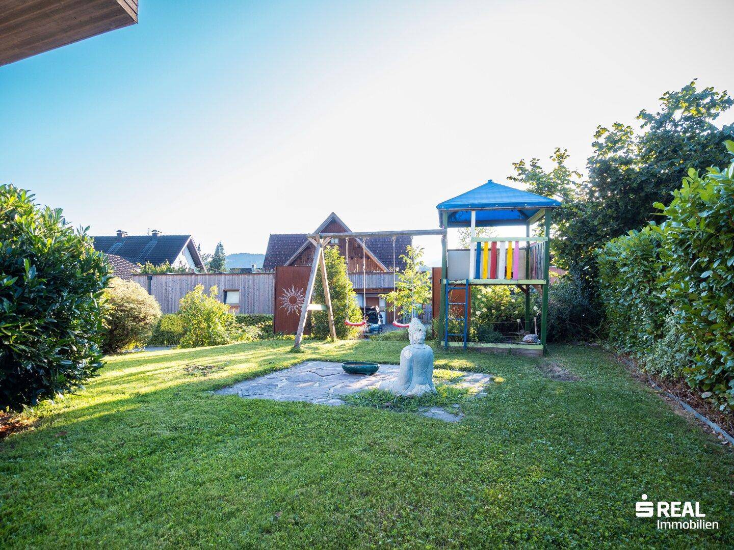 Weitläufiger Garten mit Spielplatz, gepflegtem Rasen und umgebenden Hecken.