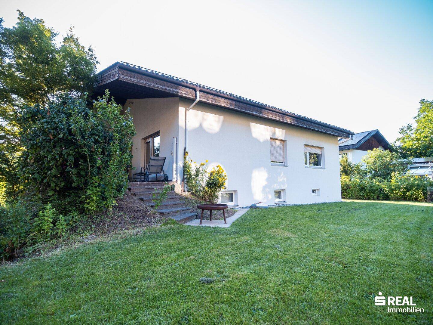 Seitlicher Blick auf das Haus mit kleiner überdachter Terrasse und gepflegtem Rasenbereich.