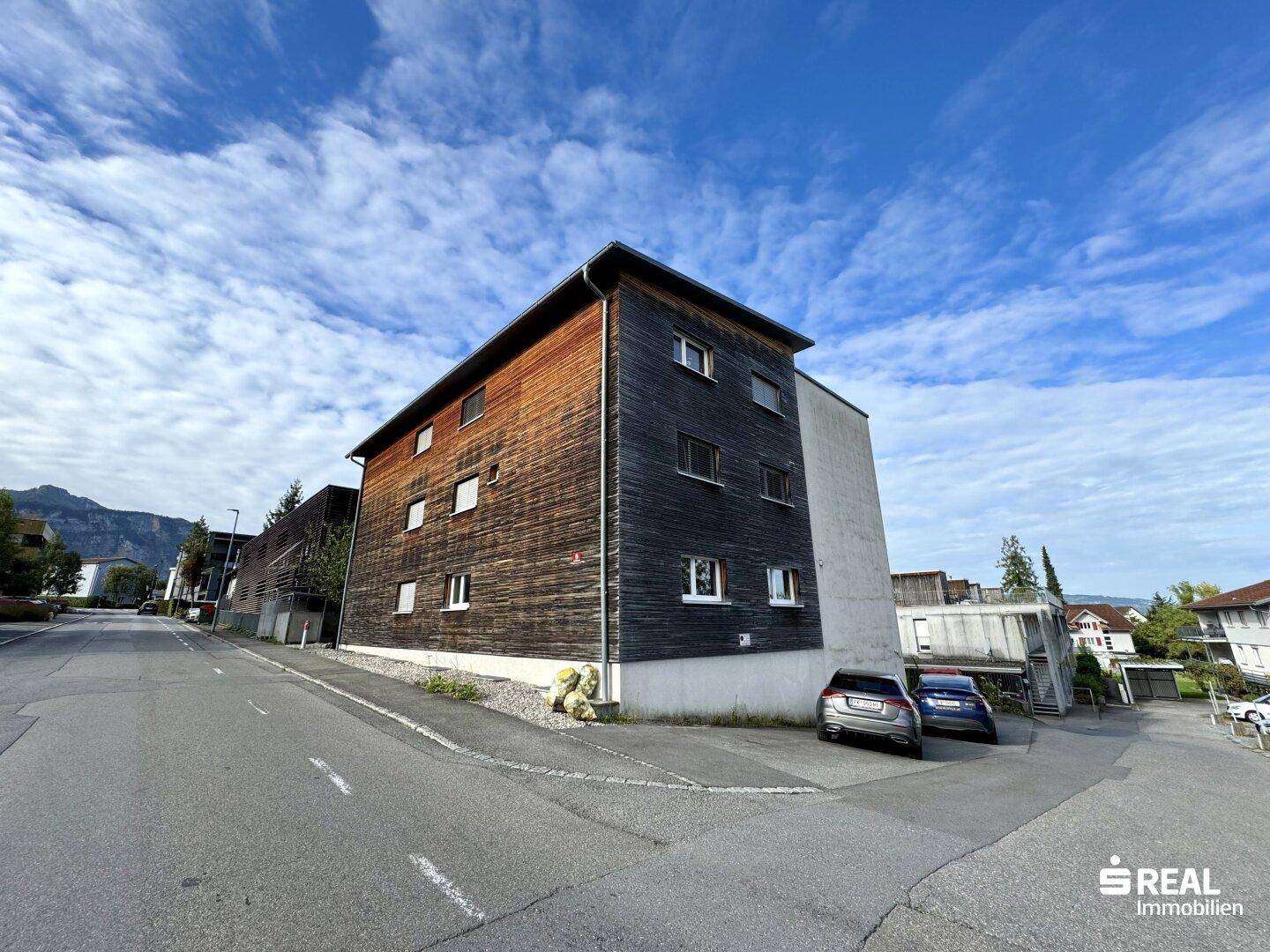 Seitenansicht eines Wohngebäudes mit Holzfassade und Fenstern.