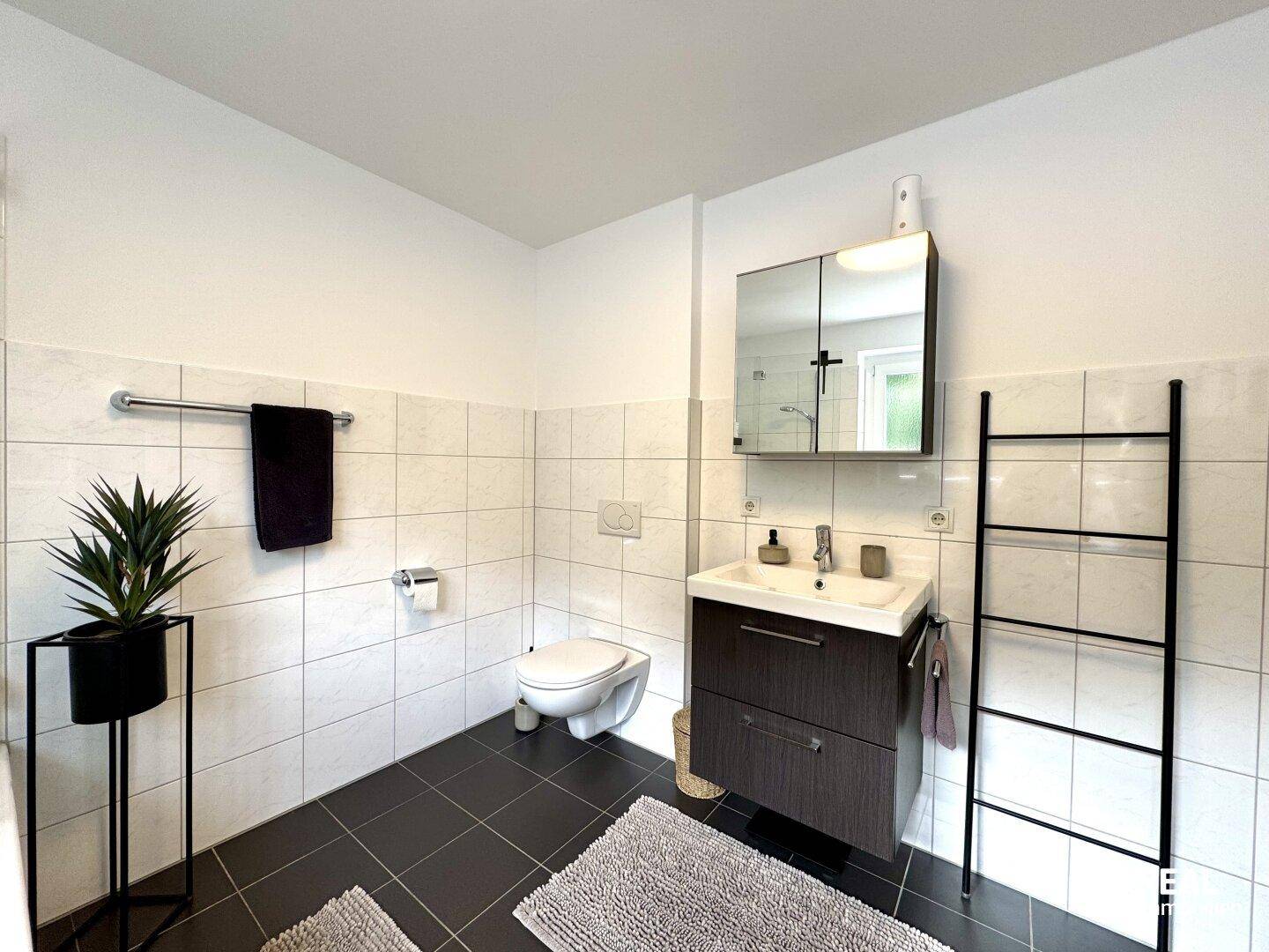 Helles Badezimmer mit WC, Waschbecken und Spiegelschrank.