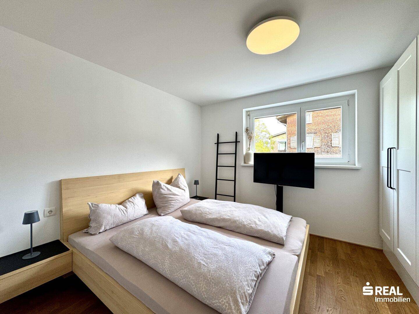 Gemütliches Schlafzimmer mit Doppelbett, Holzboden und Fenster.