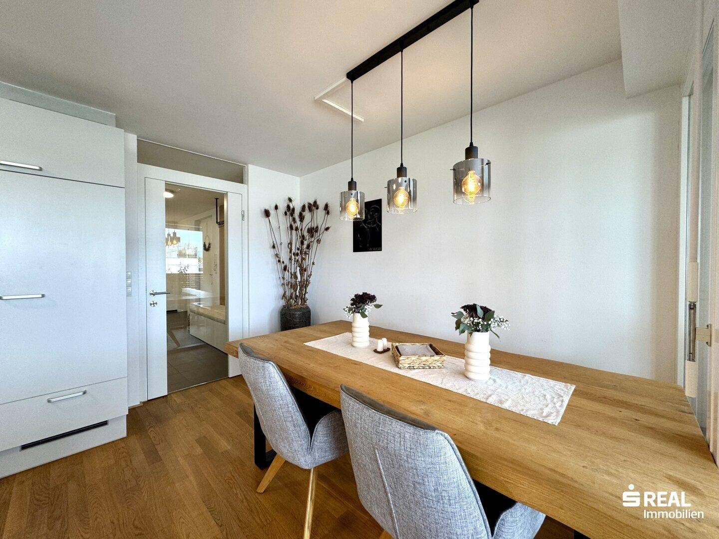 Essbereich mit Holztisch und Stühlen, angrenzend an eine moderne Küche.
