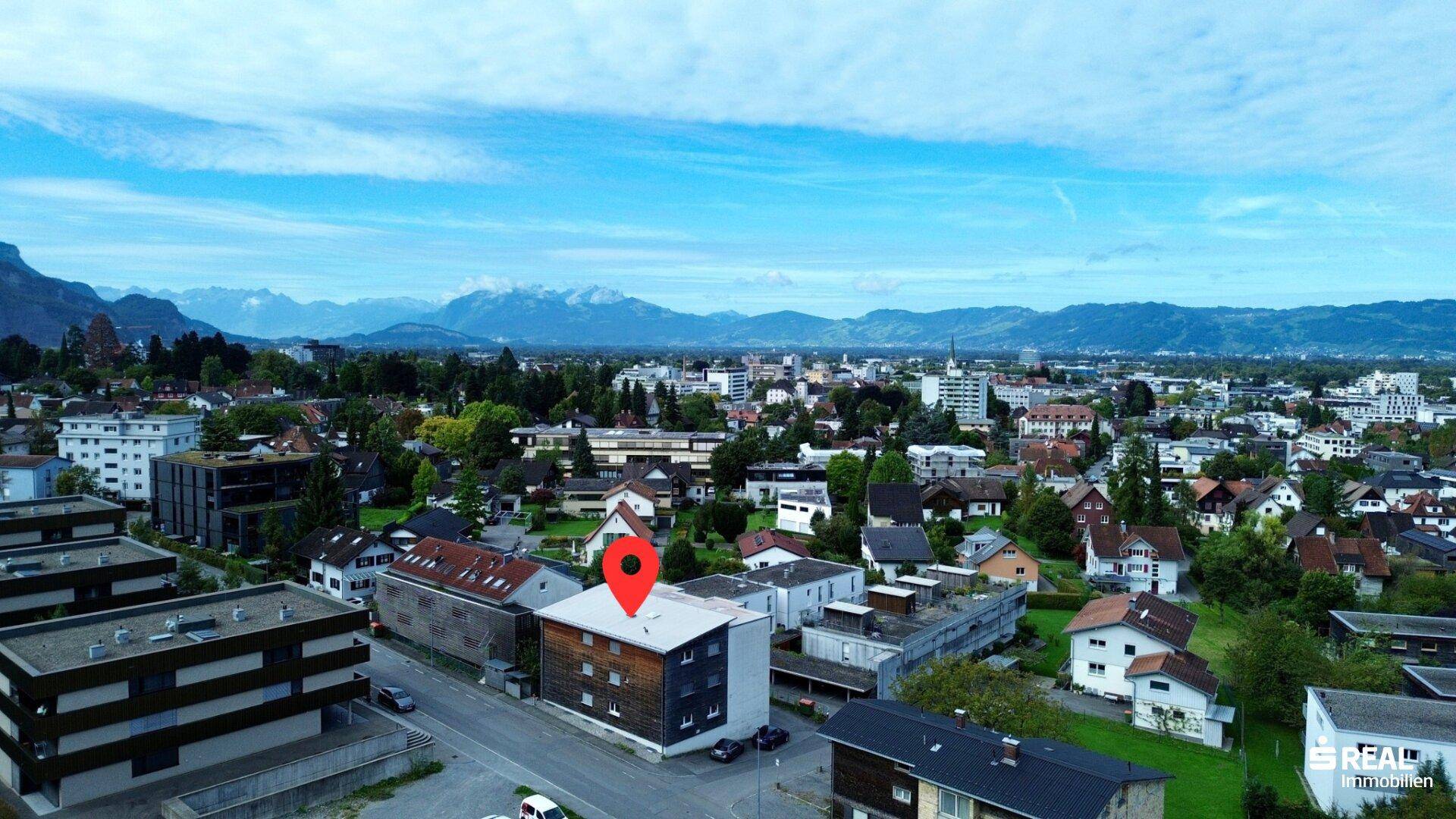 Luftaufnahme des Wohngebäudes in einer städtischen Umgebung mit Bergblick im Hintergrund.