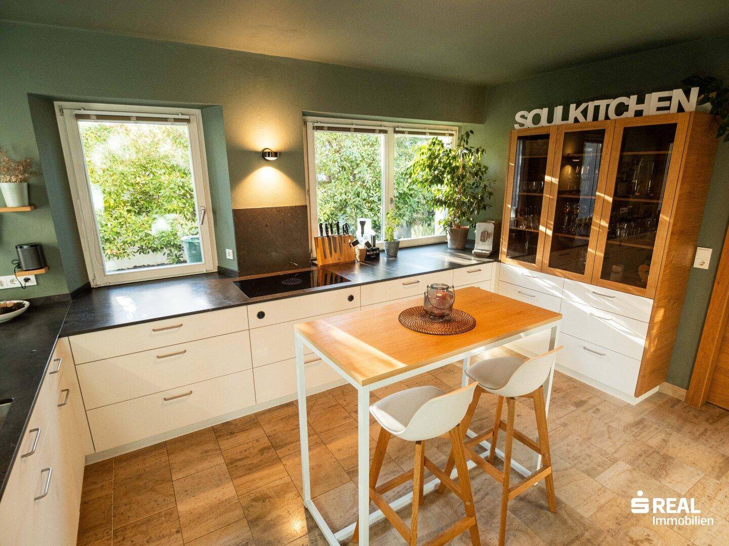 Moderne Küche mit weißen Schränken, grünen Wänden und einer praktischen Kücheninsel.