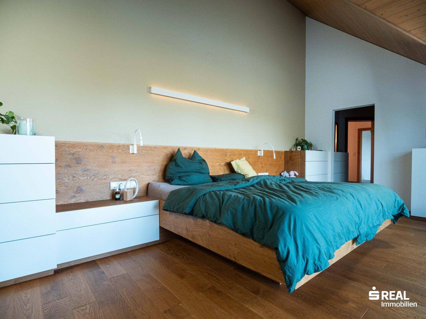 Gemütliches Schlafzimmer mit Holzbett, Dachschräge und warmem Holzboden.