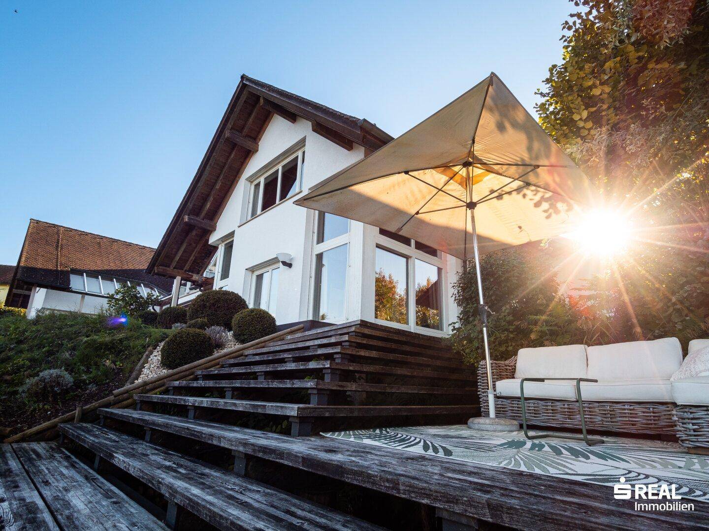 Gemütliche Sonnenterrasse mit Holzdeck und bequemen Gartenmöbeln, ideal zum Entspannen.