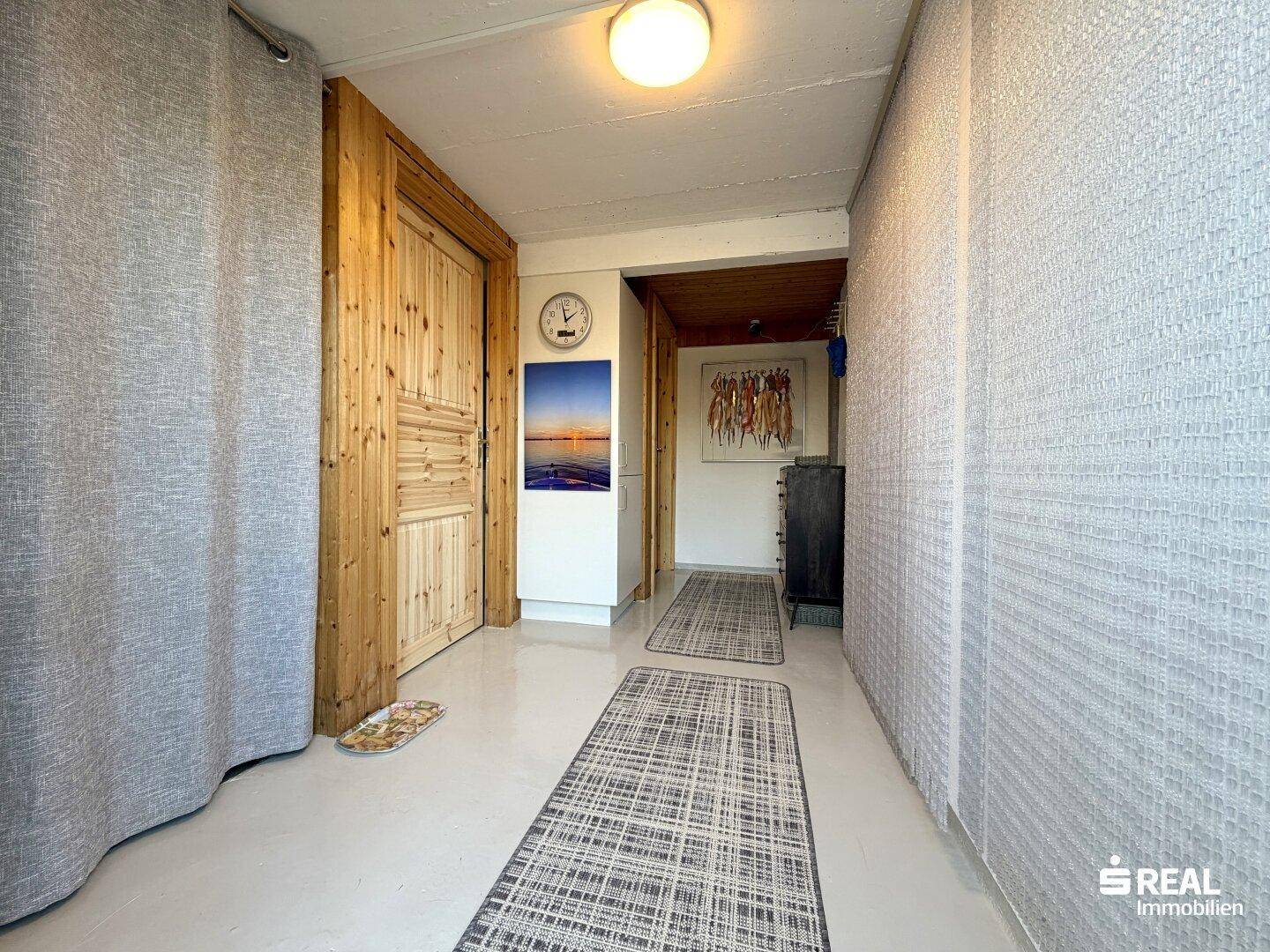 Heller Flur mit Holztür, Teppichläufern und schlichter Wandgestaltung.