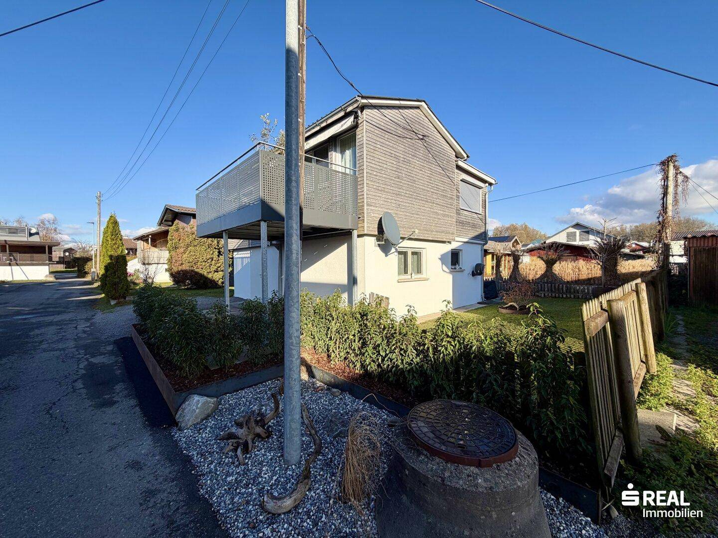 Ansicht des Hauses von der Straße mit Balkon und gepflegter Hecke im Vorgarten.