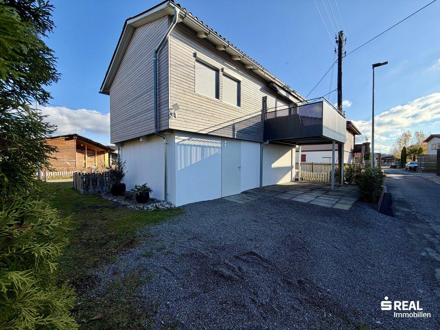 Ansicht des Hauses mit Zufahrt, Parkplatz und modernem Balkon.