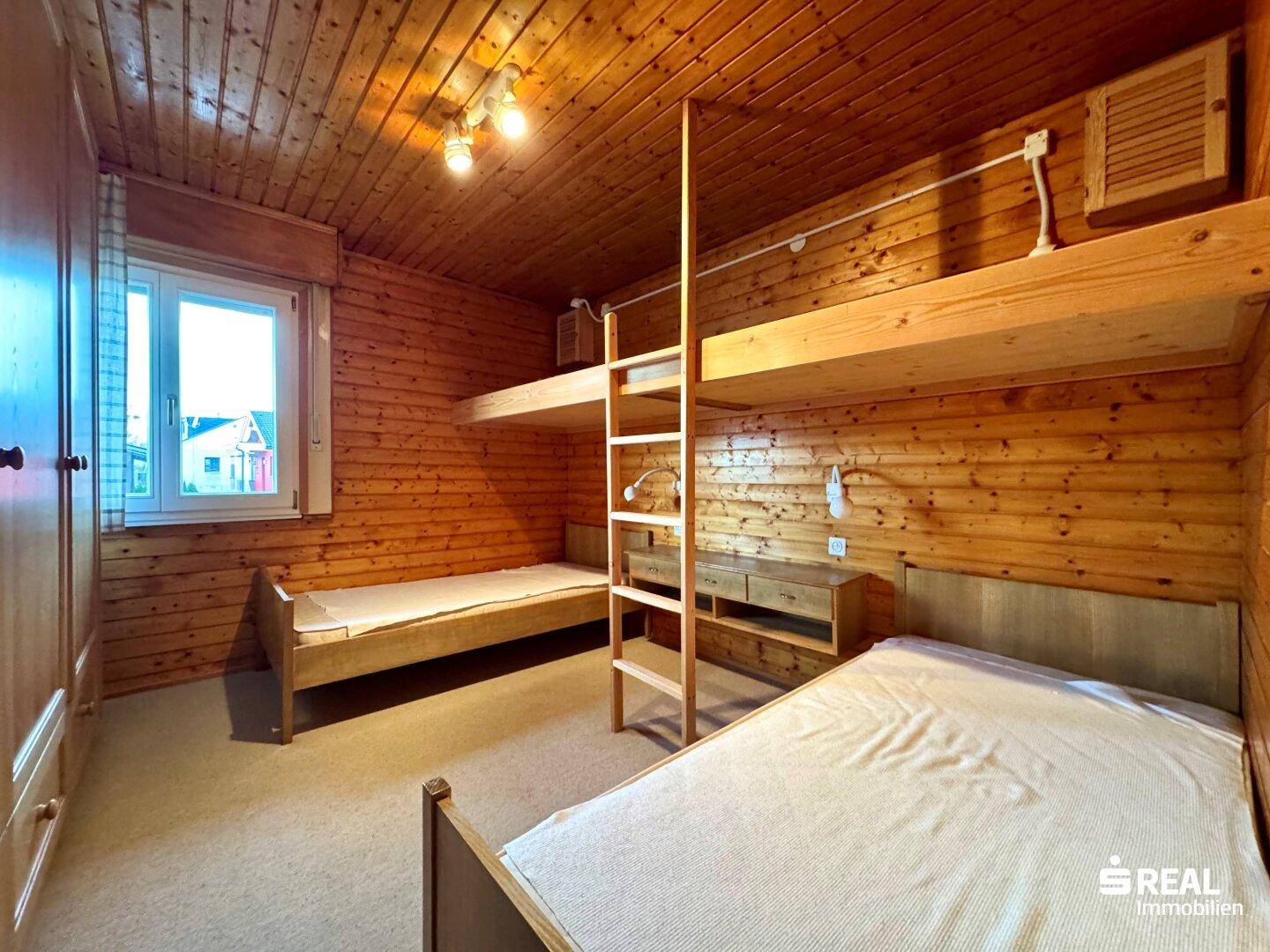 Schlafzimmer mit Holzverkleidung, Etagenbetten und Teppichboden.