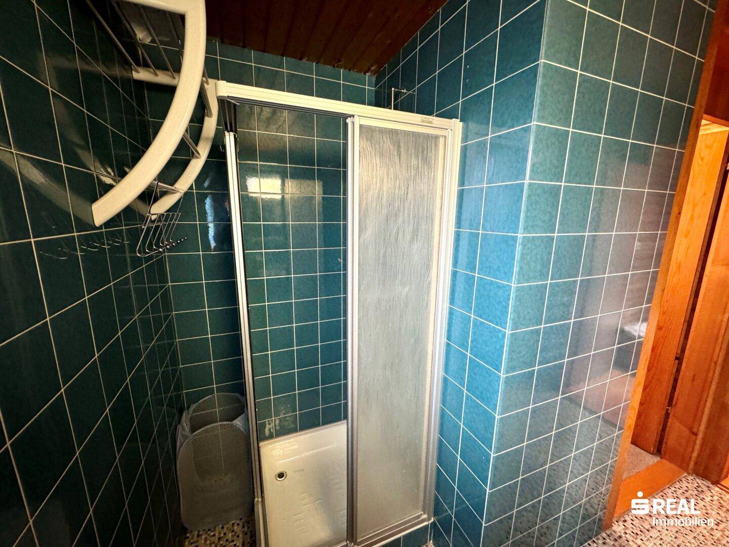Badezimmer mit blauen Fliesen und Duschkabine.