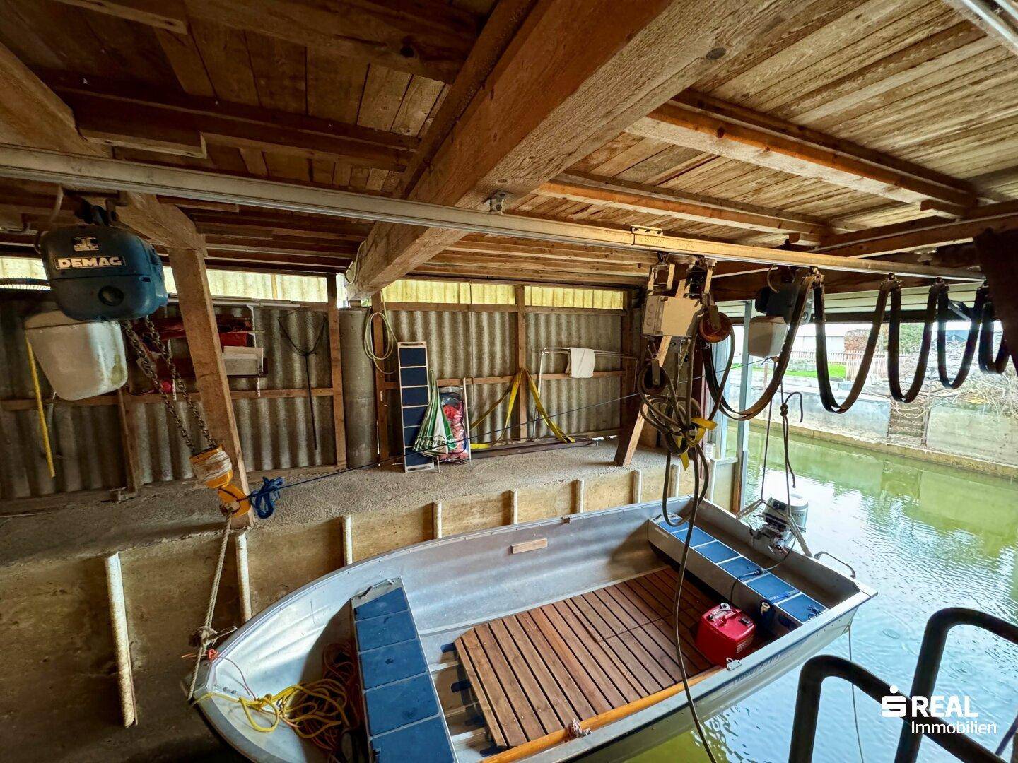 Bootsgarage mit hängendem Motorboot und rustikaler Holzkonstruktion.