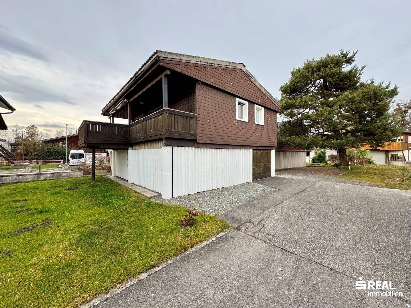 Ansicht des Hauses mit Bootsgarage, Zufahrt und umliegender Grünfläche.