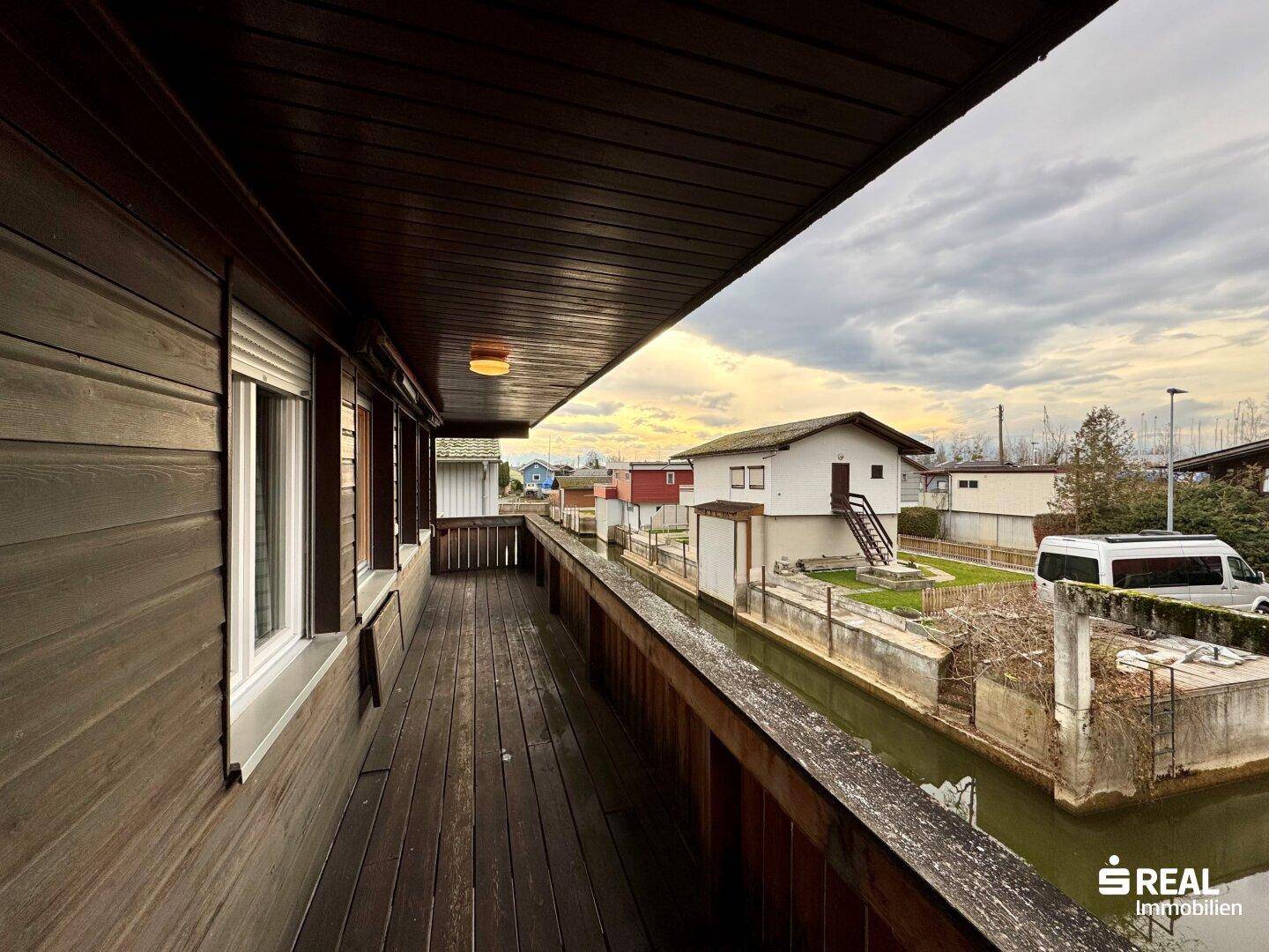 Langer Holzbalkon mit Blick auf die umliegenden Häuser und den Kanal.