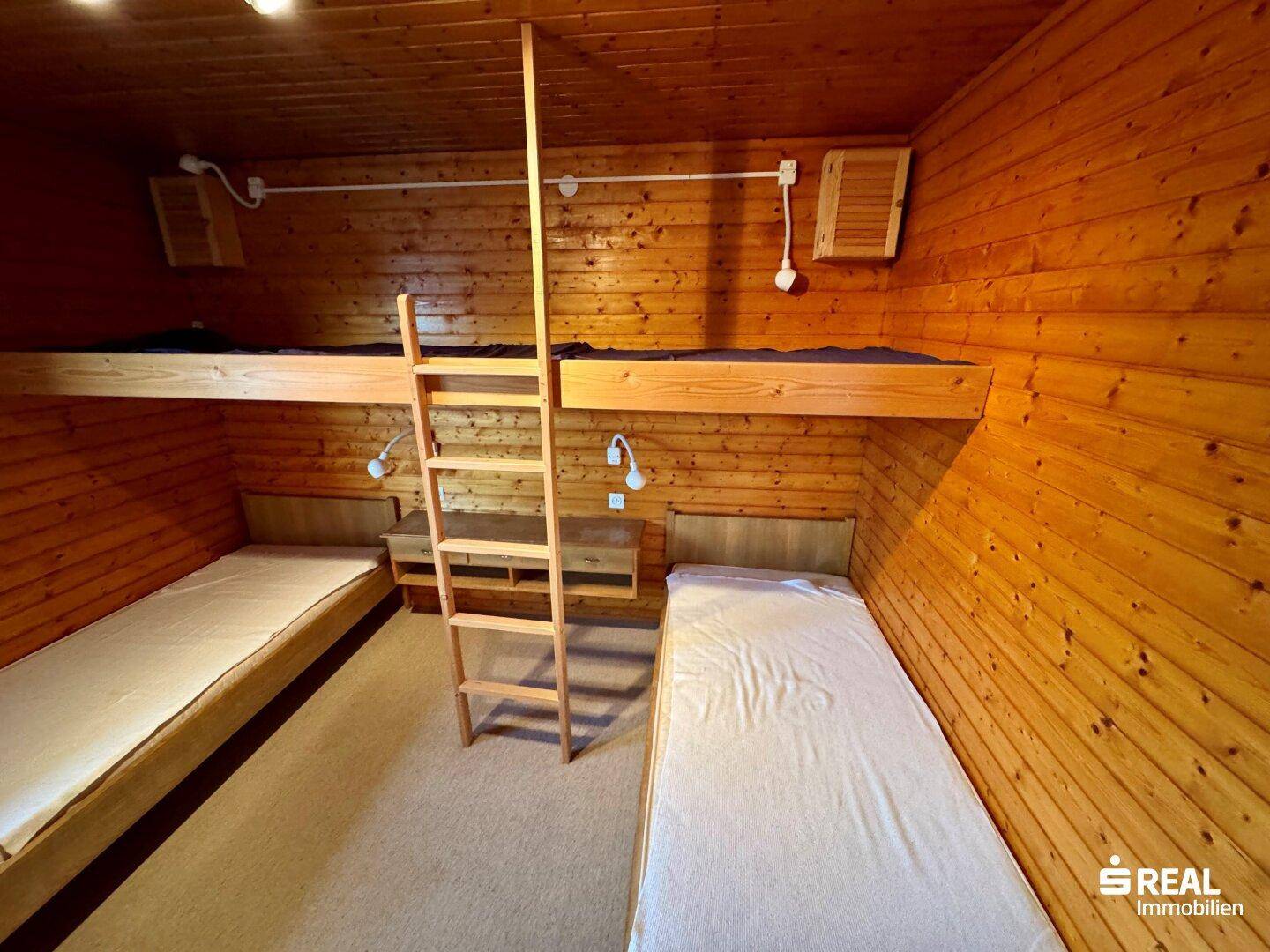 Schlafzimmer mit Holzverkleidung, zwei Etagenbetten und Teppichboden.