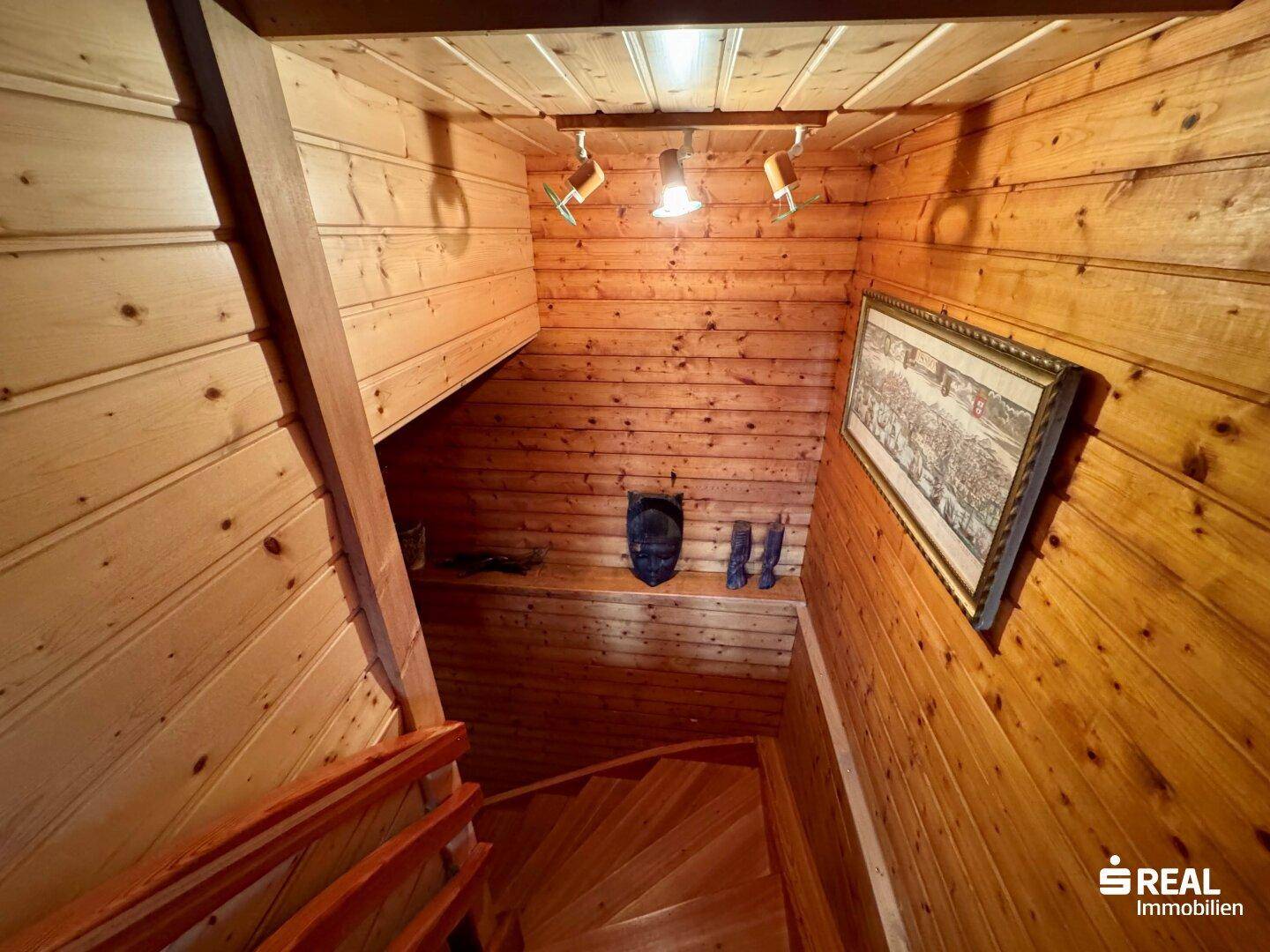 Holztreppe führt nach oben, umgeben von rustikaler Holzverkleidung.