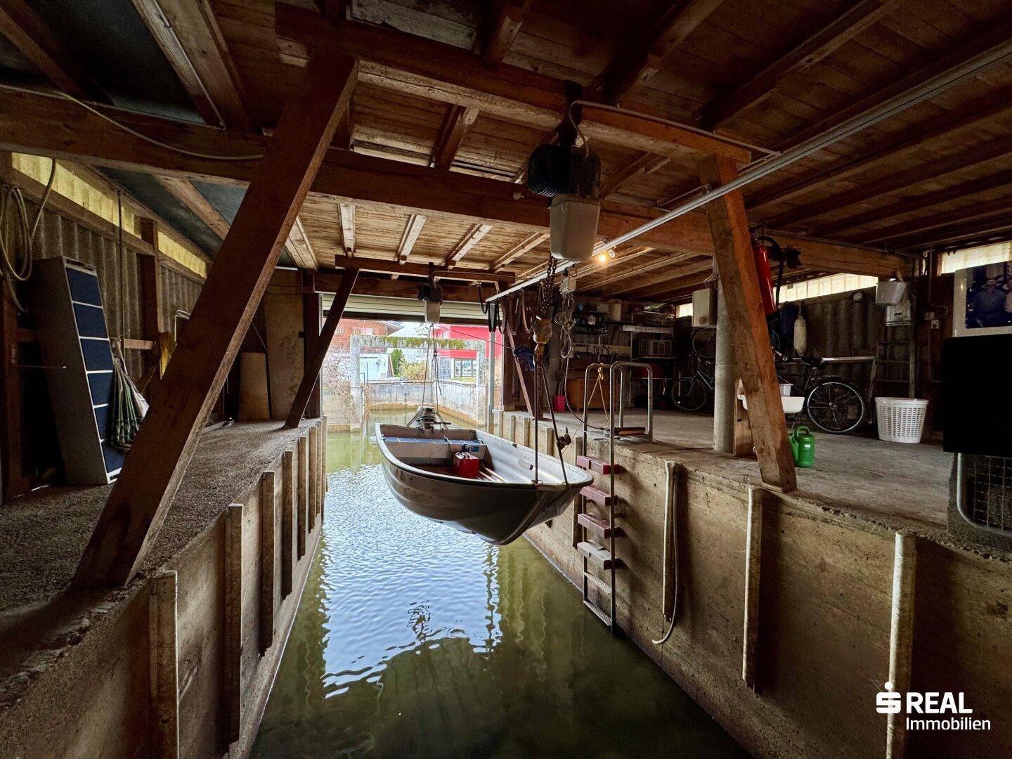 Innenansicht der Bootsgarage mit hängendem Boot und Holzkonstruktion.