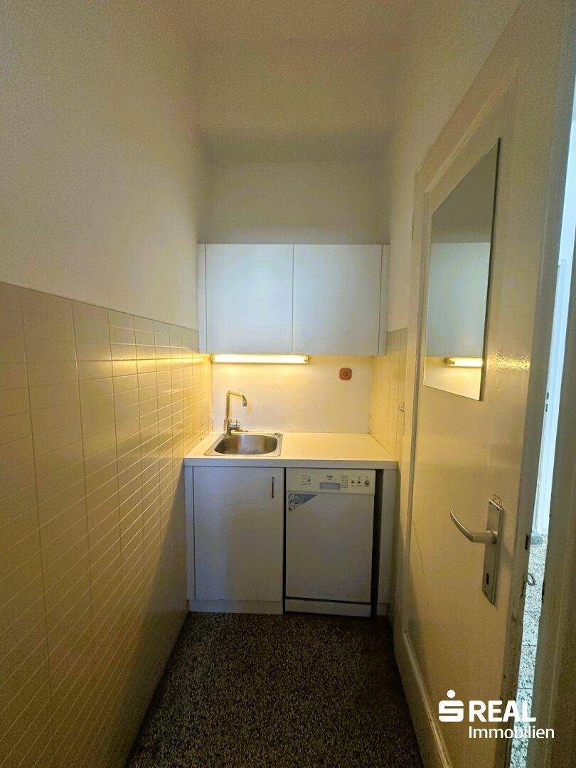 Kleine Teeküche mit Spüle, Unterschränken und Geschirrspüler, ideal für kurze Pausen.