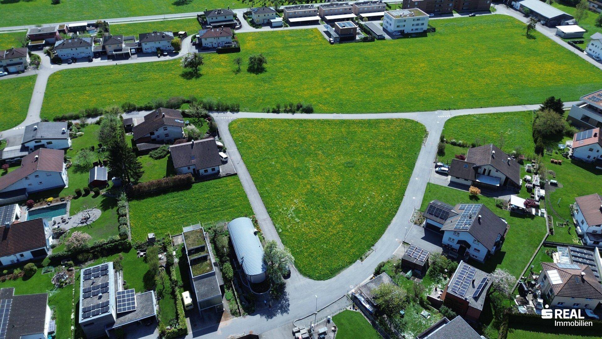 Weitläufige Luftaufnahme des Baugrundstücks mit umliegender Wohnbebauung und landwirtschaftlichen Flächen.