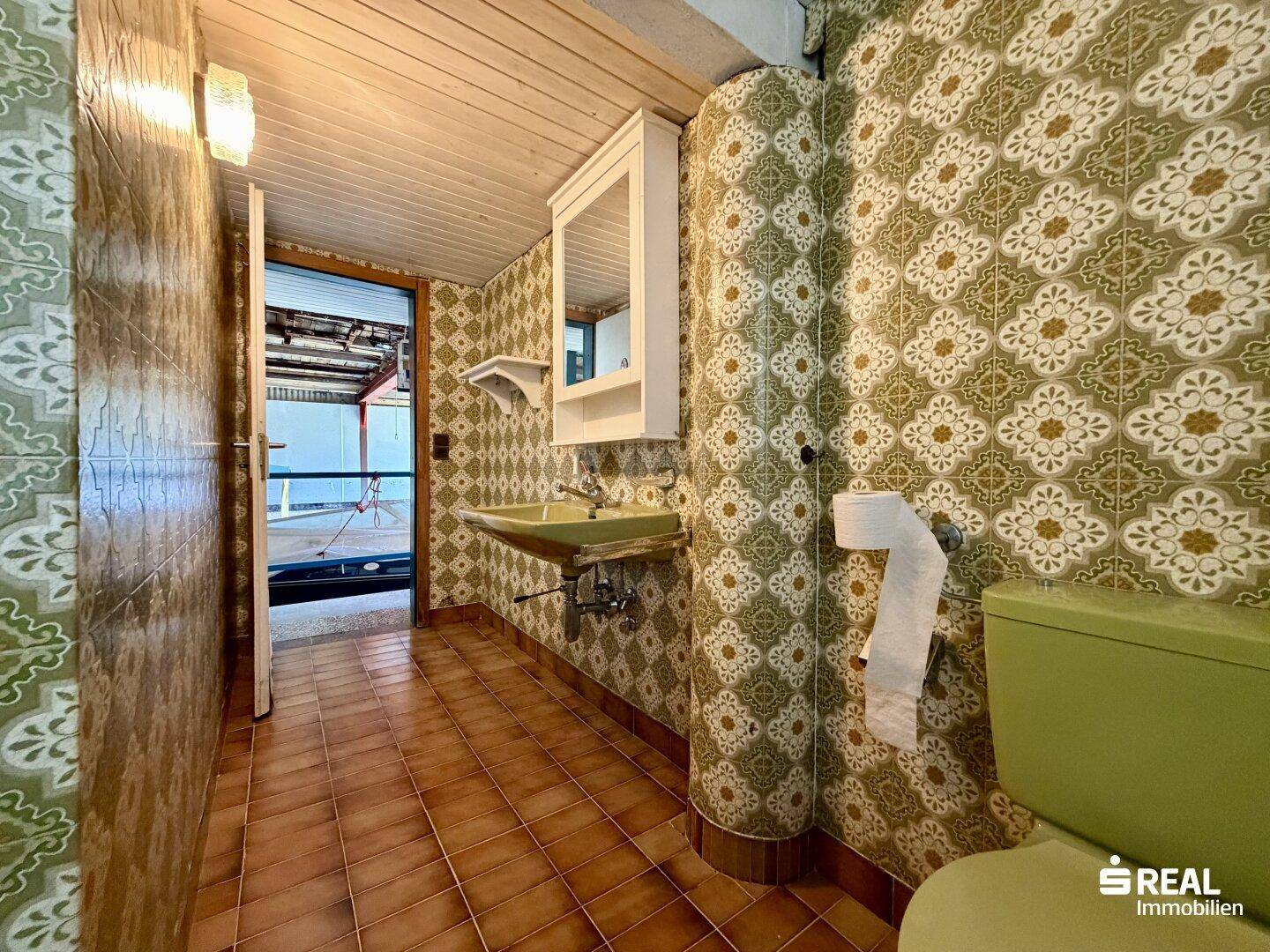 Badezimmer mit retro Fliesen, Waschtisch und Toilette.