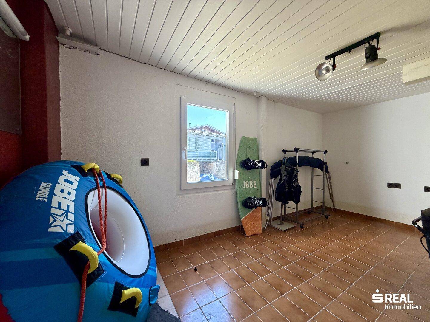 Raum mit Fliesenboden und Fenster, genutzt für Sportausrüstung und Lagerung.