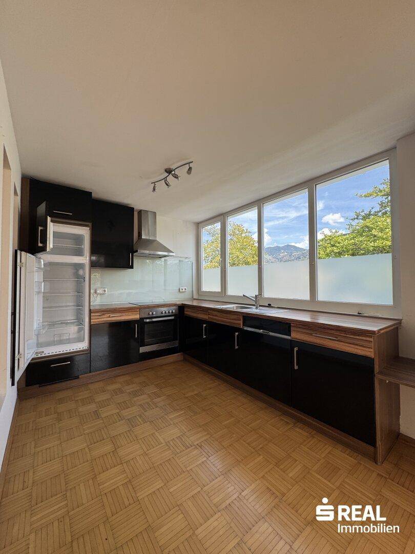 Geräumige Küche mit schwarzen Einbauschränken, Holz-Arbeitsplatten und Bergblick.