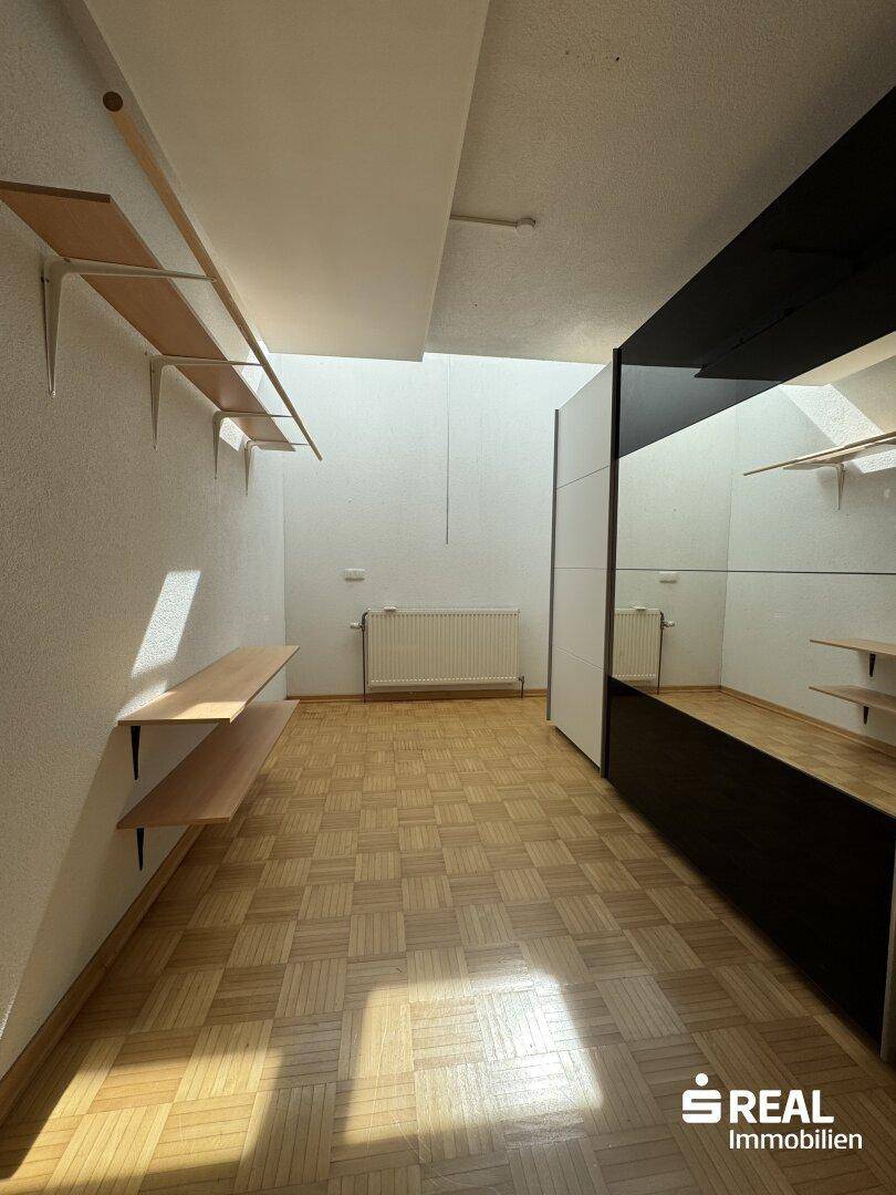 Ankleidezimmer mit Parkettboden, Regalen und Spiegelflächen für Kleidung.