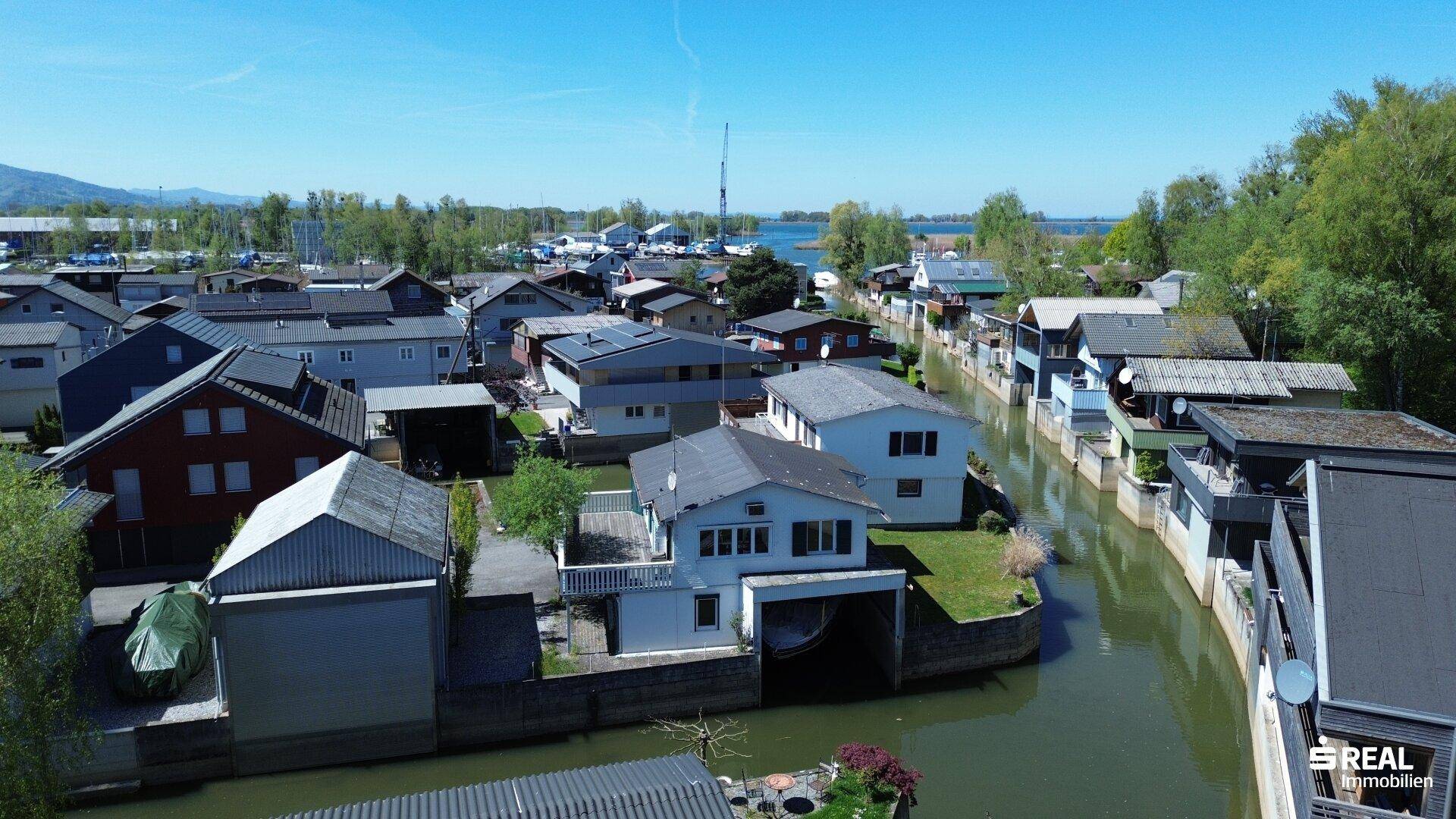 Luftaufnahme der Siedlung am Wasser mit vielen Häusern und Bootsanlegestellen.