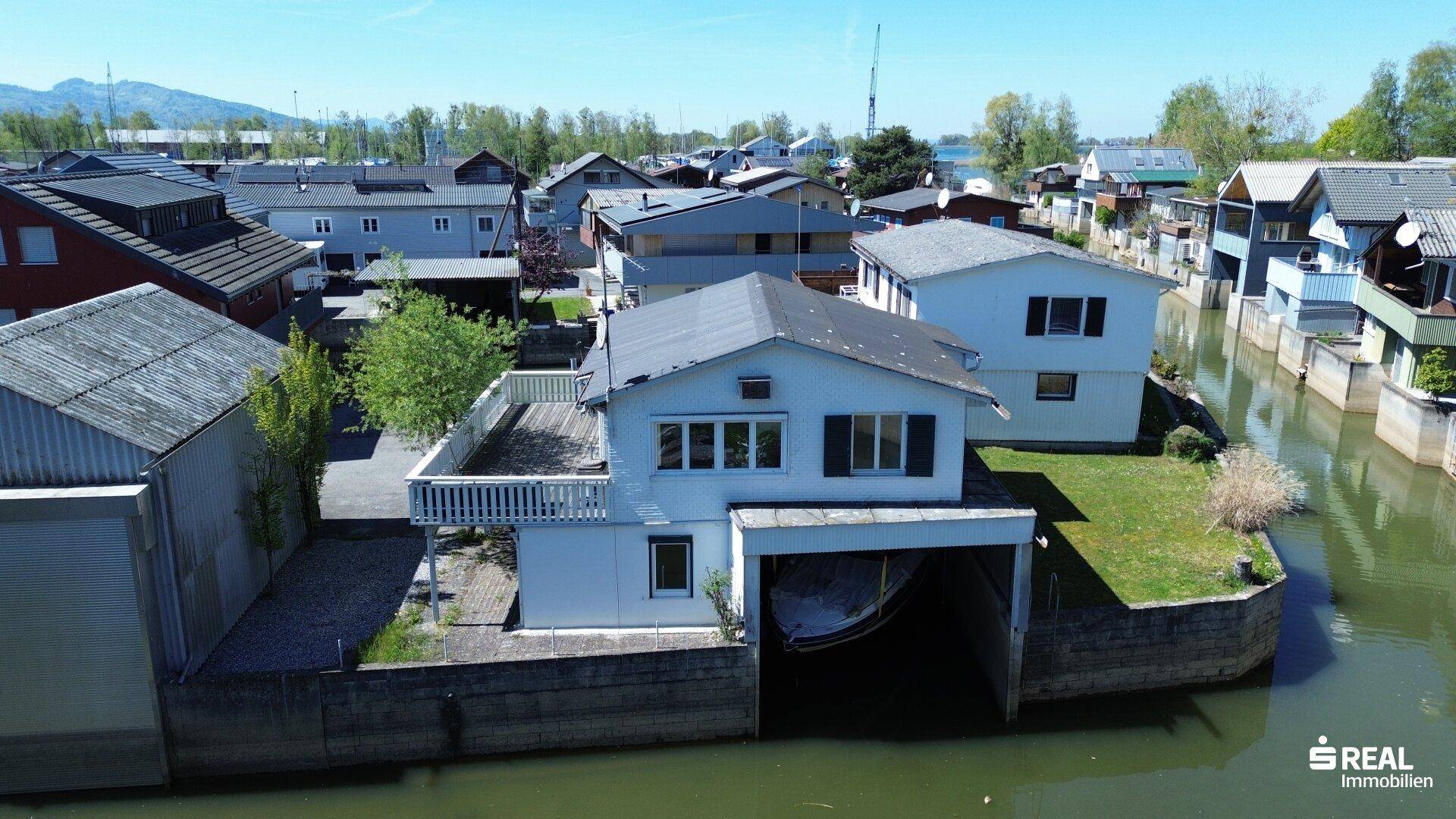 Vogelperspektive des Hauses am Kanal mit Bootsgarage und umliegenden Gärten.