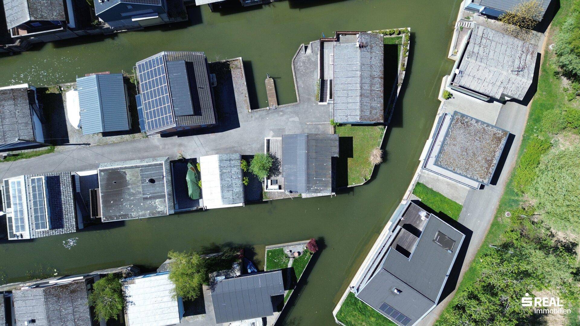 Übersicht der Wassersiedlung mit zahlreichen Häusern, Kanälen und Solaranlagen auf Dächern.