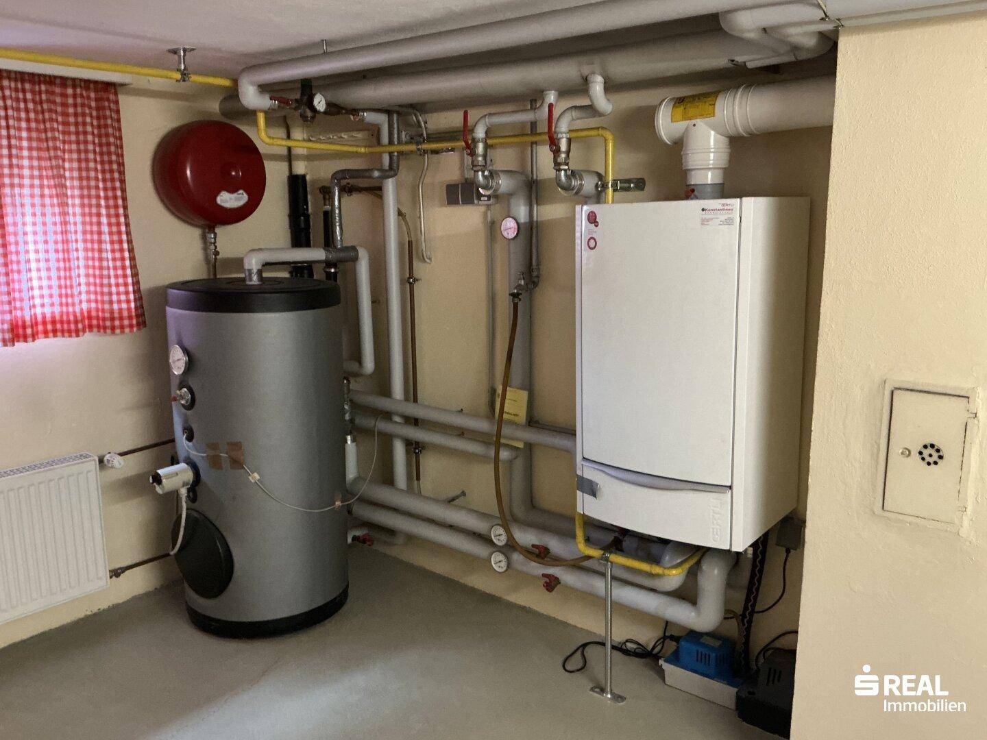 Heizungsraum mit Gastherme, Warmwasserspeicher und sichtbaren Rohrleitungen.