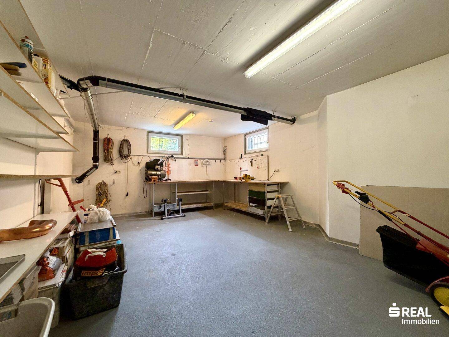Geräumiger Hobbyraum oder Werkstatt im Keller mit Regalen, Werkbank und vielseitigem Stauraum.