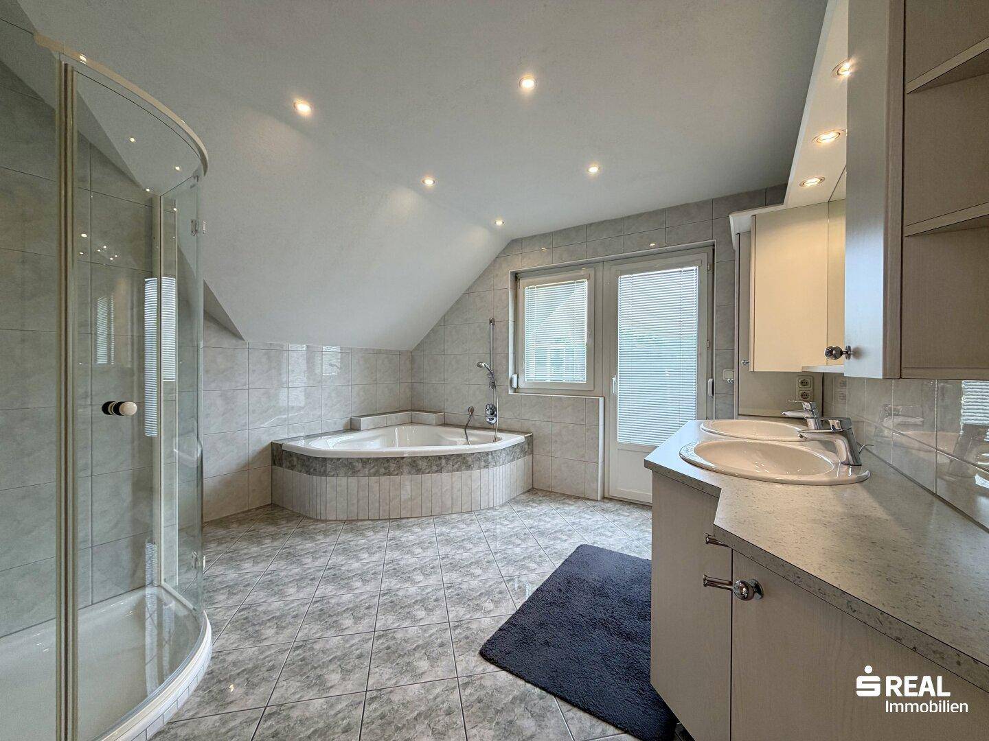 Geräumiges Badezimmer im Dachgeschoss mit Eckbadewanne, Dusche und Doppelwaschbecken.